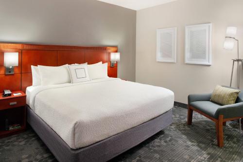 a bedroom with a large bed and a chair at Courtyard by Marriott Raleigh Cary in Cary