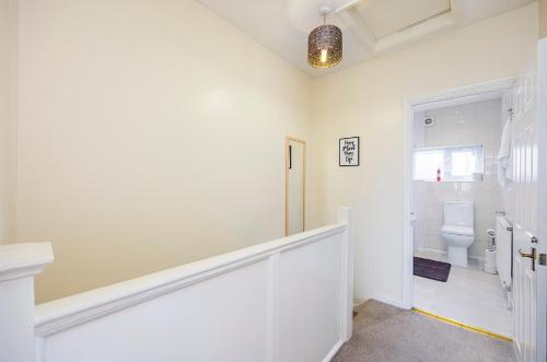 biała łazienka z toaletą i schodami w obiekcie 3 BR House w Parking Close to Shops w mieście Goodmayes
