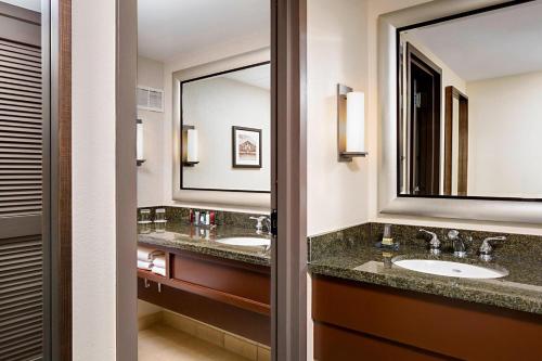 baño con 2 lavabos y espejo grande en Houston Marriott Westchase, en Houston