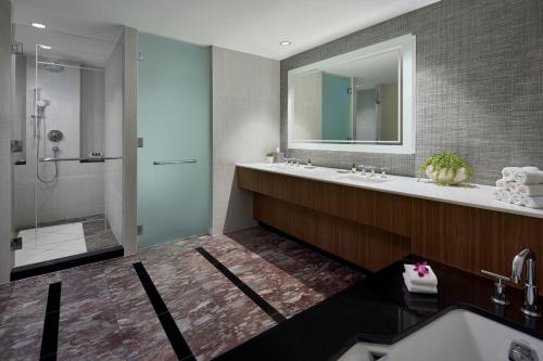 a bathroom with a sink and a shower and a mirror at The Opus Westchester, Autograph Collection in White Plains