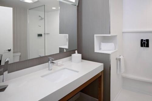 a white bathroom with a sink and a mirror at Courtyard by Marriott Dallas Downtown/Reunion District in Dallas