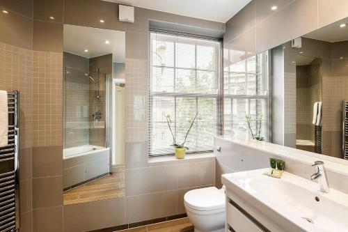 a bathroom with a toilet and a sink and a window at Chelsea - Sloane Avenue by Viridian Apartments in London