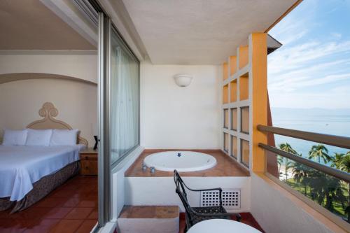 a room with a balcony with a bed and a tub at Club Regina Puerto Vallarta in Puerto Vallarta