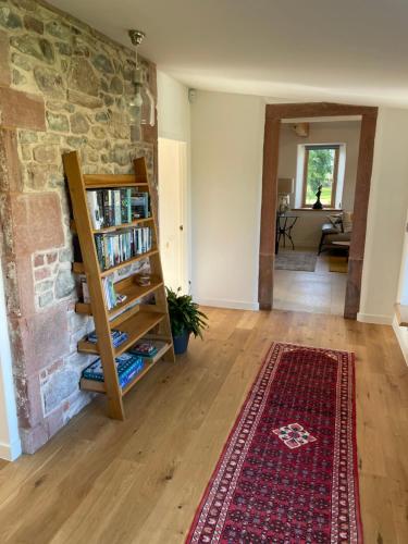 a living room with a stone wall and a book shelf at The Stables - Luxury Cottage in Dumfries