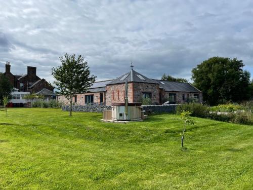 a large brick house with a green yard at The Stables - Luxury Cottage in Dumfries
