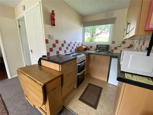 a small kitchen with a stove and a sink at 15 The Drive, Penstowe Holiday Park, Kilkhampton, Bude, Cornwall in Bude