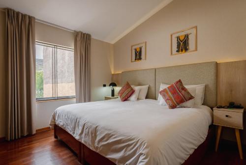 - une chambre avec un grand lit blanc et une fenêtre dans l'établissement Torre Dorada Cusco, à Cusco