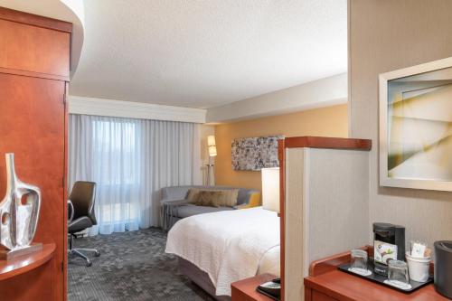 um quarto de hotel com uma cama e uma sala de estar em Courtyard Milwaukee Airport em Milwaukee