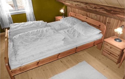 a wooden bed with white sheets on it in a room at Awesome Home In Skiftun With House Sea View in Hjelmeland