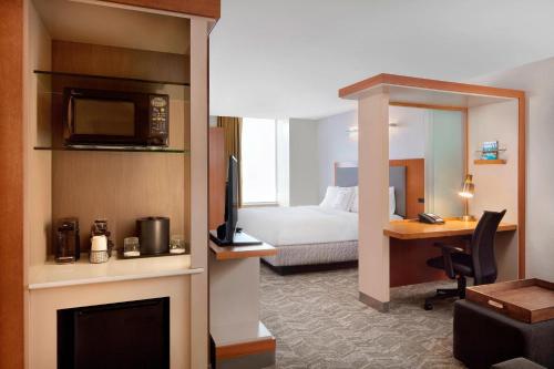 a hotel room with a bed and a desk with a television at SpringHill Suites Indianapolis Downtown in Indianapolis