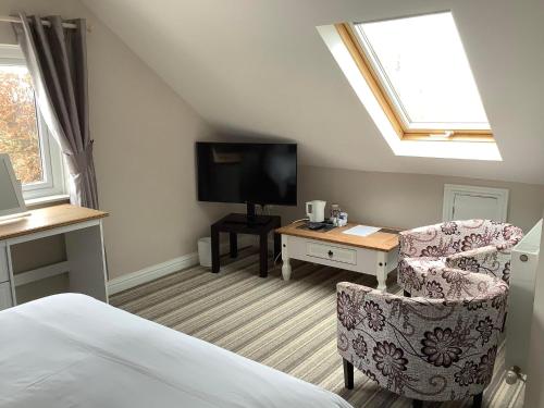 a bedroom with a bed and a chair and a tv at New Overlander Inn in Tenby