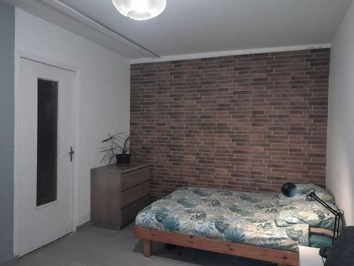 Un dormitorio con una pared de ladrillo y una cama en Studio agréable et fonctionnel à 5km des plages, en Lannion
