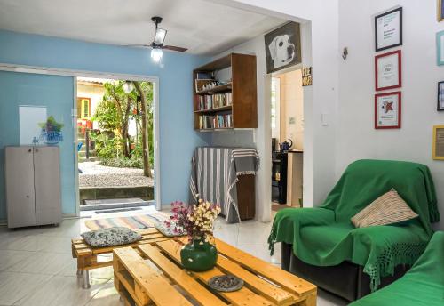 uma sala de estar com uma mesa e uma cadeira verde em Eco Pousada Estrelas da Babilônia no Rio de Janeiro