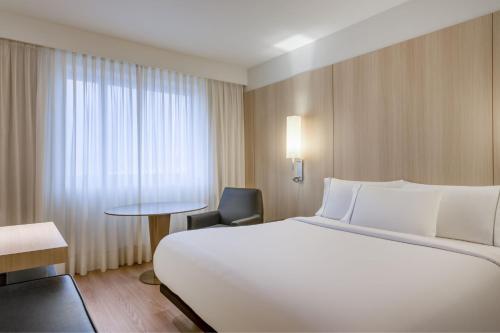 una habitación de hotel con una gran cama blanca y una silla en AC Hotel Córdoba by Marriott, en Córdoba