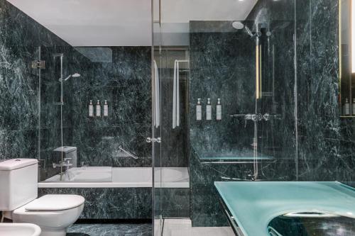 a bathroom with a shower and a toilet and a tub at AC Hotel Córdoba by Marriott in Córdoba