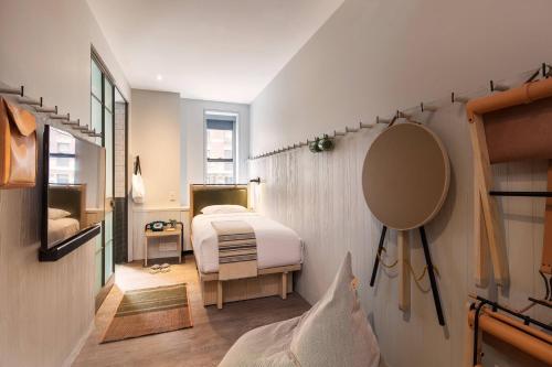 a small bedroom with a bed and a mirror at MOXY NYC Times Square in New York