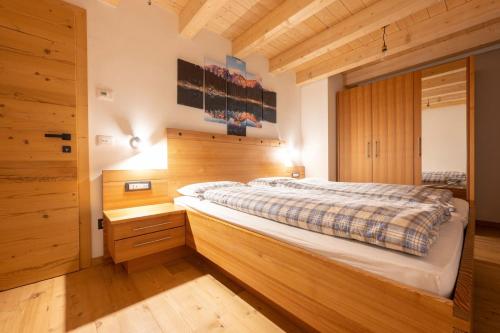 1 dormitorio con 1 cama grande y paredes de madera en Ciasa Marta en Vigo di Fassa