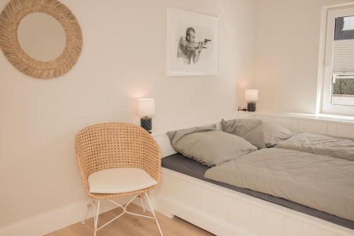 Habitación con cama, silla y espejo. en Appartement salt mit Südterrasse, en Timmendorfer Strand