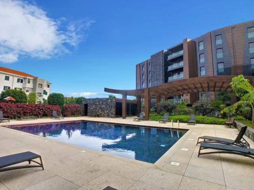 a swimming pool with two chairs and a building at Lynx Barreiros by LovelyStay in Funchal