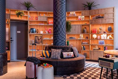 a living room with a couch and a book shelf at Moxy The Hague in The Hague