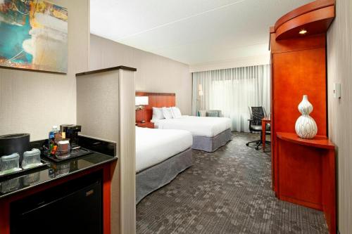 a hotel room with two beds and a desk and a room at Courtyard Pittsburgh Greensburg in Greensburg