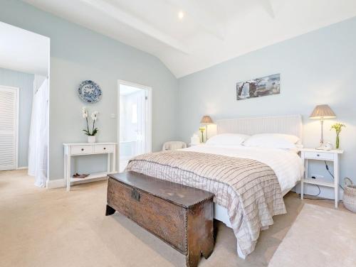 FishbourneにあるPalm Tree Cottageの白いベッドルーム(ベッド1台、テーブル2台付)