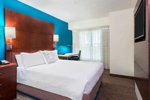 Habitación de hotel con cama grande y escritorio. en Residence Inn by Marriott Fort Myers, en Fort Myers