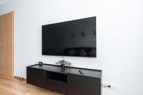 a black entertainment center with a flat screen tv on a wall at Cozy&Chic - A modern apartment with a garden terrace in Rīga