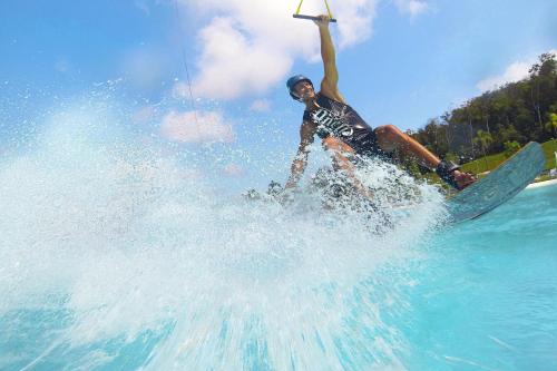 a man riding a wave on a surfboard in the water at Natra Bintan, a Tribute Portfolio Resort in Lagoi