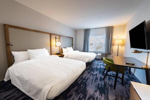 a hotel room with two beds and a desk and a television at Fairfield Inn & Suites by Marriott Phoenix West/Tolleson in Phoenix