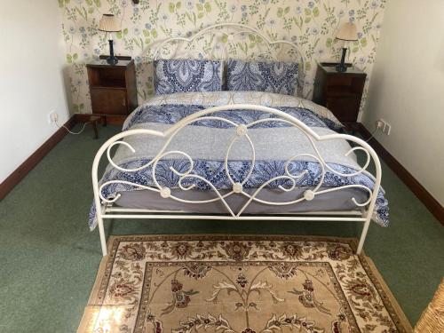 a bedroom with a white bed with a blue comforter at Delightful Pretty Cottage in Banbury