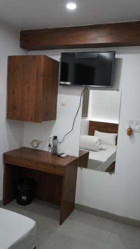 Habitación con escritorio y TV en la pared. en POD N BEYOND SMART HOTEL @BISTUPUR en Jamshedpur