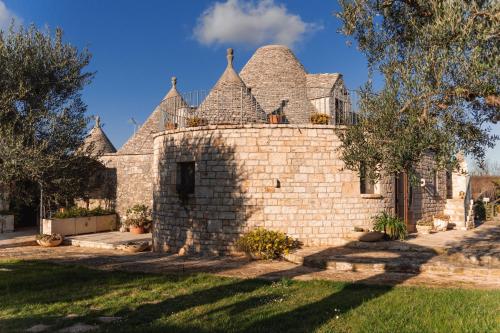 una casa de piedra con techo y patio en Masseria Montanaro, en Cisternino