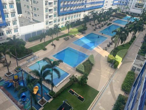 - une vue sur deux piscines avec palmiers et bâtiments dans l'établissement Sea Residences by EXIN, à Manille