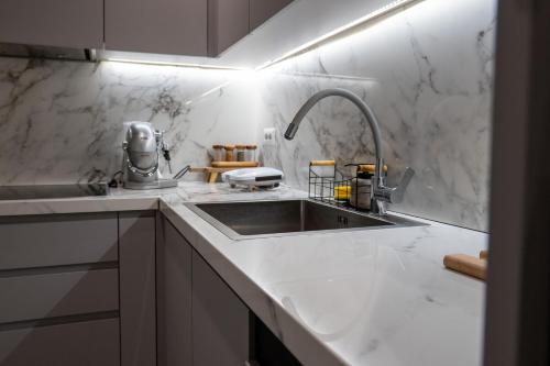 a kitchen with a sink and white marble walls at Skanderbeg Square Modern App - THE NEST in Tirana