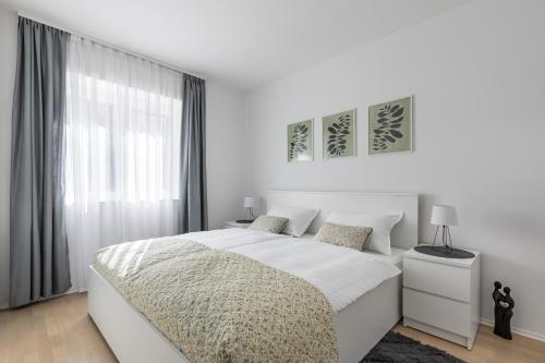 a white bedroom with a large bed and a window at Cool Suite in Split