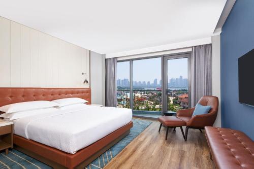 南昌市にあるFour Points by Sheraton Nanchang, Xihuのベッドと椅子付きのホテルルーム