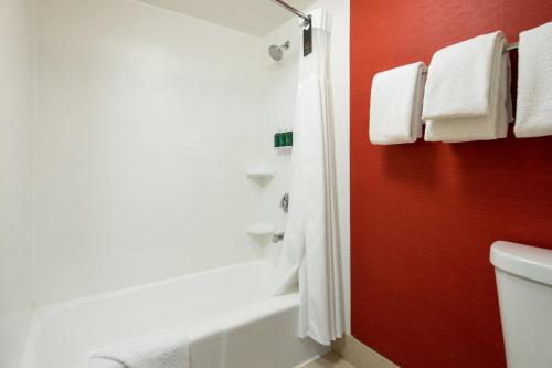 SorrentoにあるCourtyard by Marriott San Diego Sorrento Valleyの赤い壁のバスルーム(白いトイレ付)