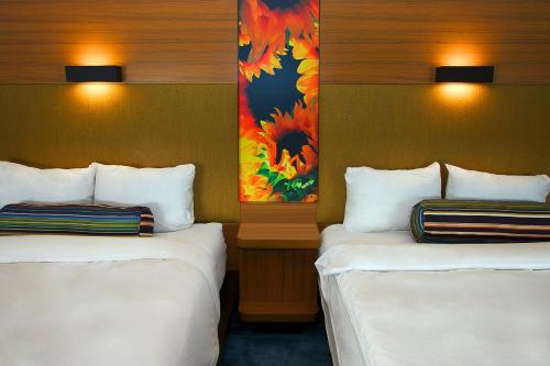 a hotel room with two beds and a painting on the wall at Aloft Tulsa in Tulsa