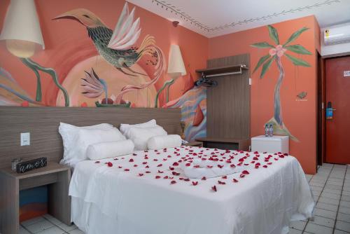 a bedroom with a bed with red rose petals on it at Hotel Areias Belas in Maragogi