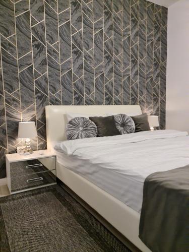 ein Schlafzimmer mit einem weißen Bett und einer Wand in der Unterkunft Global Residence Lake View in Bukarest