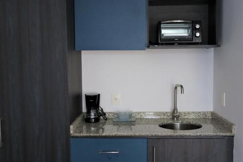 a kitchen with a sink and a microwave at Expo Satelite Hotel & Suites in Guadalajara