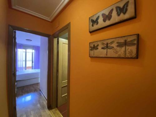 un pasillo con una pared naranja con mariposas en la pared en La Magdalena acogedor apartamento en Villaviciosa, en Villaviciosa