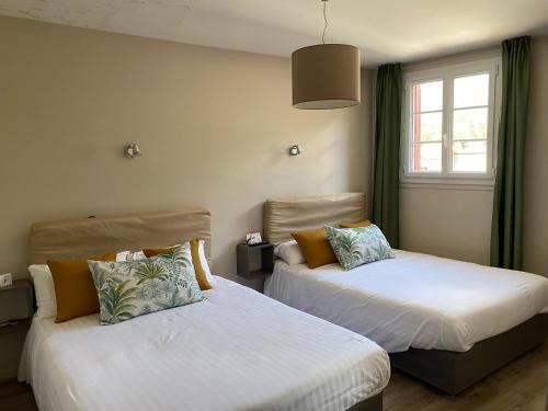 2 łóżka w pokoju z zielonymi zasłonami w obiekcie Hôtel Juantorena w mieście Saint-Étienne-de-Baïgorry
