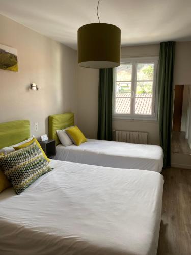 a hotel room with two beds and a window at Hôtel Juantorena in Saint-Étienne-de-Baïgorry