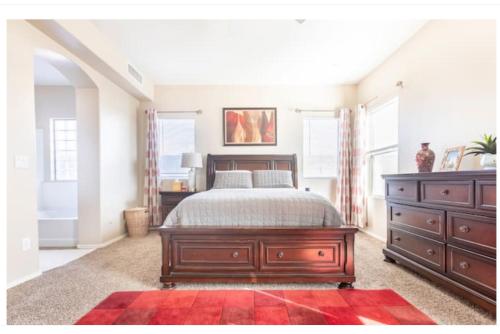 a bedroom with a bed and a dresser and windows at Olivia Jones Residence I in San Tan Valley