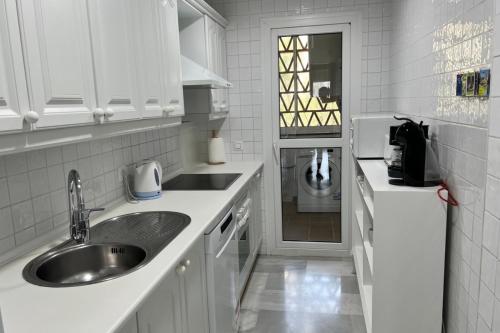 een keuken met witte kasten, een wastafel en een deur bij MI CAPRICHO 4C BEACHFRONT -Apartment with sea view - Costa del Sol in Sitio de Calahonda