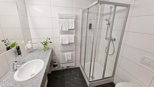 a white bathroom with a shower and a sink at Hotel Fortuna Reutlingen-Tübingen in Reutlingen