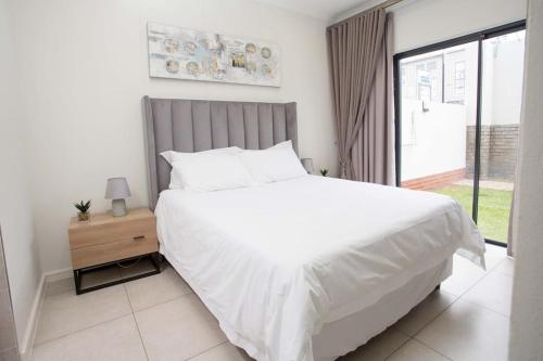 Un dormitorio con una gran cama blanca y una ventana en Secured and Fully equipped apartment- E en Lombardy East