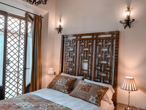 une chambre avec une tête de lit en bois et un lit avec deux lampes dans l'établissement Apartamentos en pleno centro, Aljibe Rodrigo del Campo 1B, à Grenade